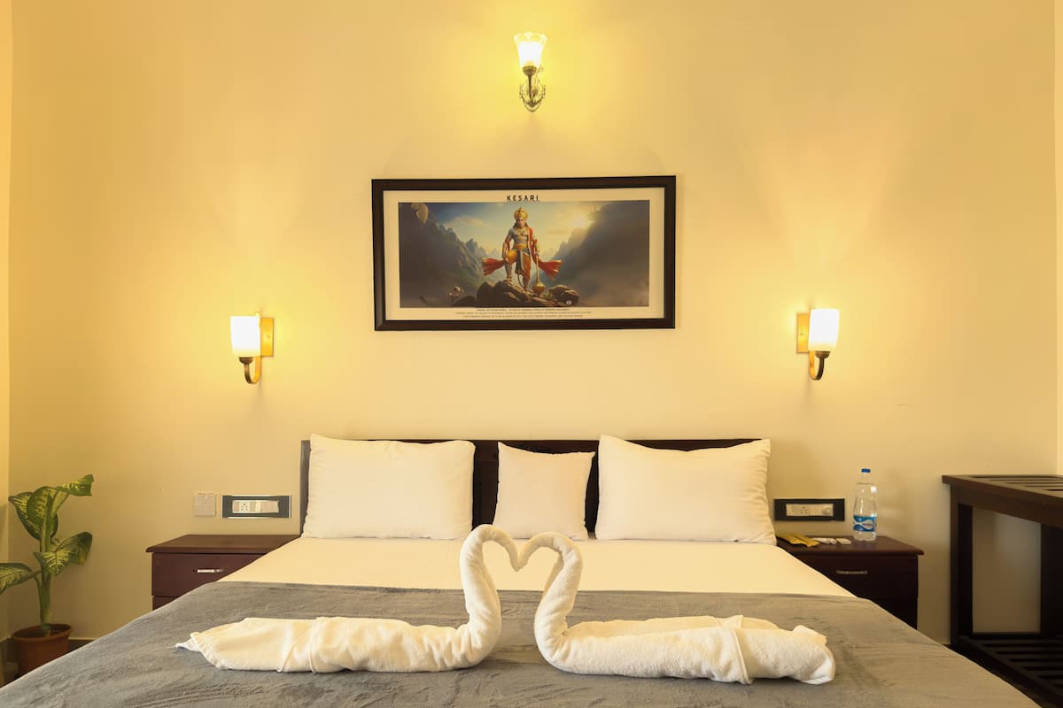 A hotel room with a bed, two nightstands, a framed picture on the wall, and a swan-shaped towel arrangement on the bed.