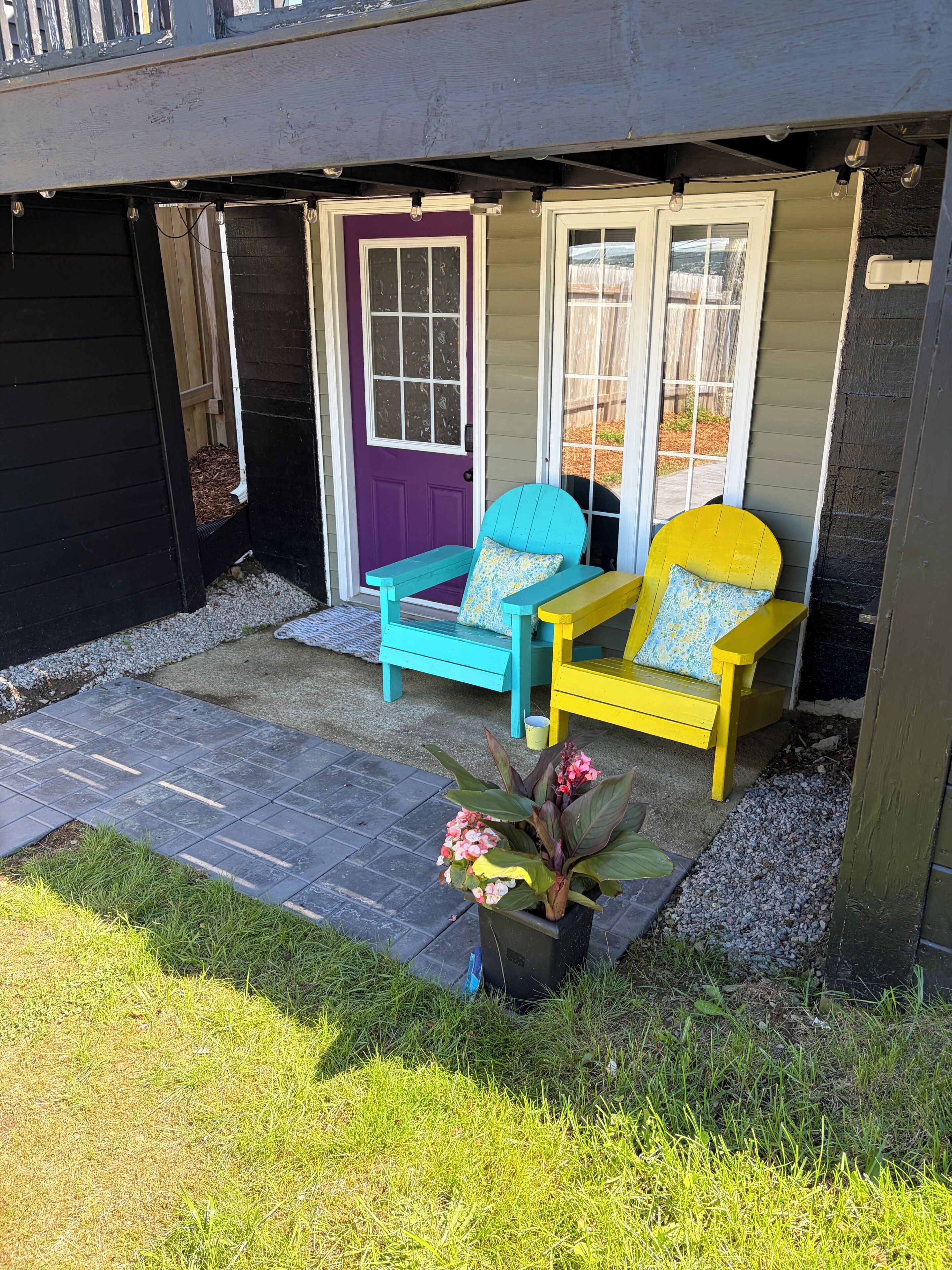 Ein Haus mit Veranda, zwei Adirondack-Stühlen, einem Blumentopf und einem Kiesweg zum Eingang.