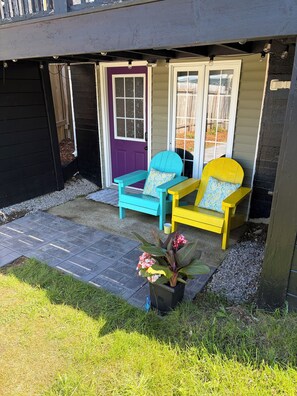 A house with a front porch featuring two Adirondack chairs, a potted plant, and a gravel pathway leading to the entrance.