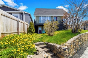 A residential house with a front yard, stone steps, and a wooden fence.