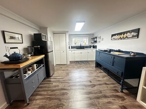 A kitchen with white cabinets, a blue refrigerator, a wooden countertop, and a blue dresser. - The Whistling Kettle | King Studio Near Downtown (St. John's)