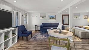 Een moderne woonkamer met een bank, fauteuils, een salontafel en een televisie.
