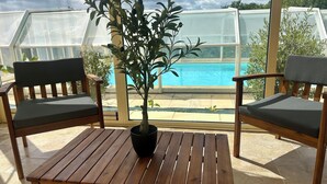 Una mesa de madera con una planta en maceta en el centro, flanqueada por dos sillas de madera con cojines.