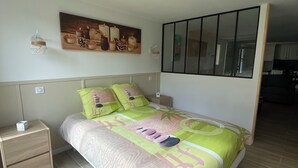 Un dormitorio con cama, mesita de noche, lámpara de pared y un cuadro.