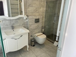 A bathroom with a white sink, a toilet, a shower, and a mirror. - Arena Modern Hotel (Istanbul)