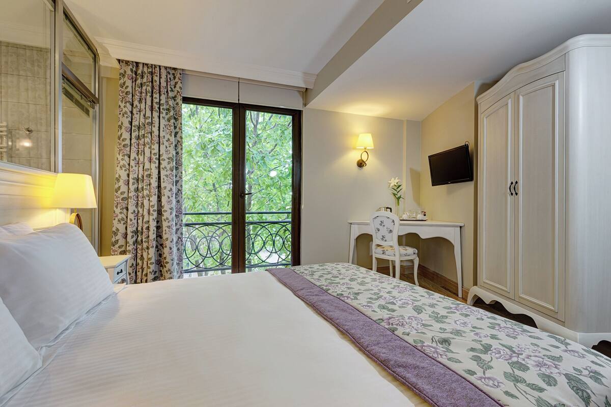 Une chambre d’hôtel comprenant un lit, un bureau, une chaise, un téléviseur et une armoire.