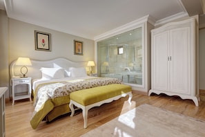 A bedroom with a bed, bedside tables, a bench, a wardrobe, and a glass shower enclosure. - Arena Modern Hotel (Istanbul)