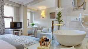 Camera d'albergo con un lavandino bianco grande, una televisione, una scrivania con lampada e un letto con biancheria a fiori.