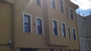 Un edificio a più piani con facciata gialla, numerose finestre e un ingresso ben visibile.
