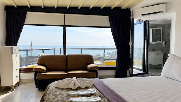 Una camera d'albergo con un letto, un divano, una cassettiera e un balcone vista mare.
