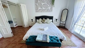 Ein Schlafzimmer mit einem Bett, einer Sitzbank, einem Kleiderschrank und einem Spiegel.
