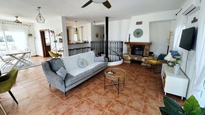 Ein Wohnzimmer mit einer Couch, einem Esstisch, einem Fernseher und einem Kamin.