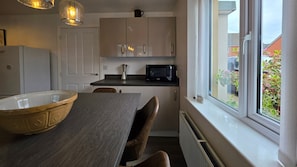 Eine kompakte Küche mit einer großen Schüssel, einer Mikrowelle und einem Fenster mit Ausblick.