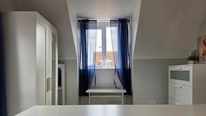 A small, bright room with a window, a radiator, and a white cabinet.