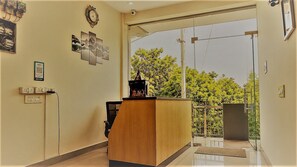 A reception area with a wooden desk, a clock, and framed pictures on the wall. - Casa Bella  (gurugram)