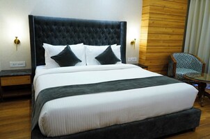 Una habitación de hotel con una cama grande, un panel decorativo de madera y una silla.