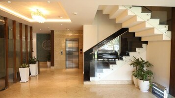 Un interior moderno con suelo de mármol, una escalera y plantas en macetas.