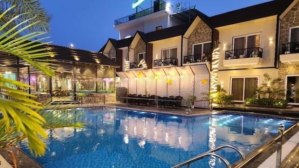 Un hotel con piscina, asientos al aire libre y una fachada bien iluminada.