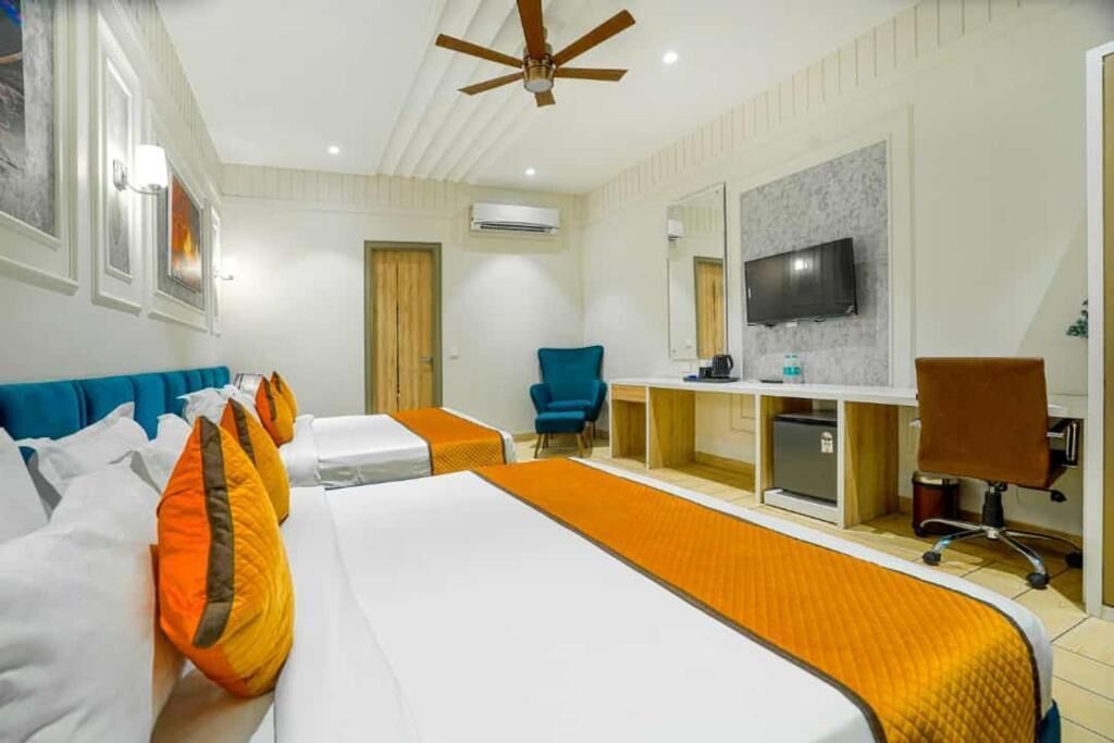 A hotel room with a bed, a desk, a chair, a television, and a ceiling fan.
