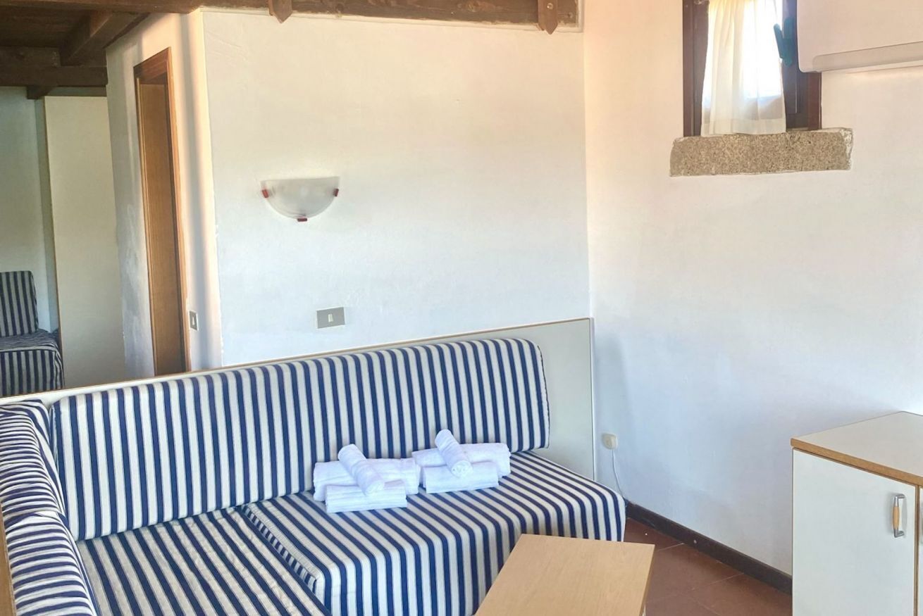 Ein gestreiftes Sofa mit Handtüchern, einem kleinen Schrank und einer Wandleuchte.