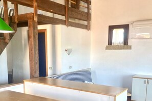 Ein Zimmer mit Holzboden, einer weißen Wand, einem Fenster mit Vorhang, einem Heizkörper und einem weißen Schrank.
