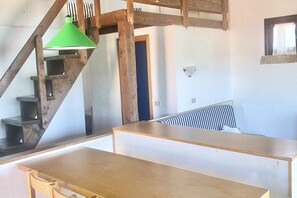 Ein Zimmer mit einer Holztreppe, einem Bett mit gestreifter Bettwäsche und einer grünen Pendelleuchte.