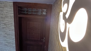 Une pièce avec un mur en pierre, une porte en bois et un luminaire fixé au mur.