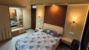 Une chambre à coucher comprenant un lit, des tables de chevet, un ventilateur de plafond et une armoire.