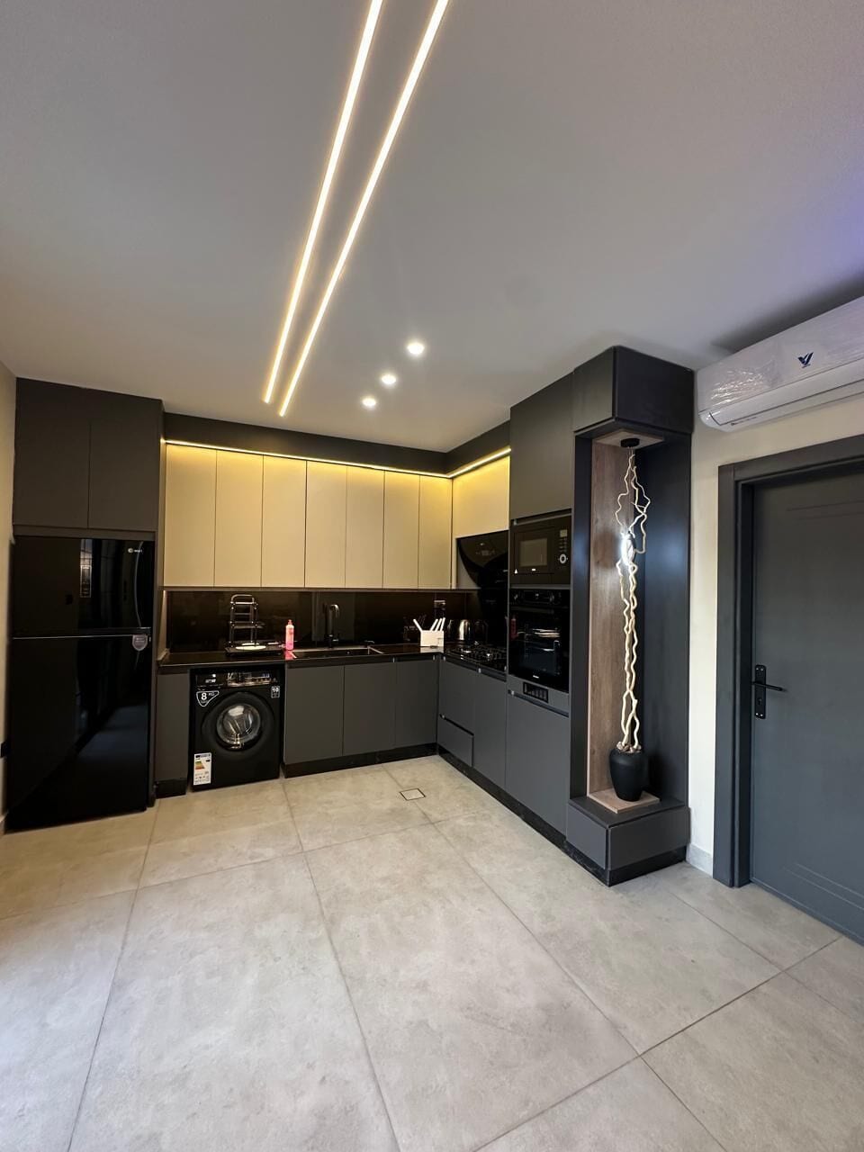 A modern kitchen with built-in appliances, a washing machine, and a unique light sculpture.