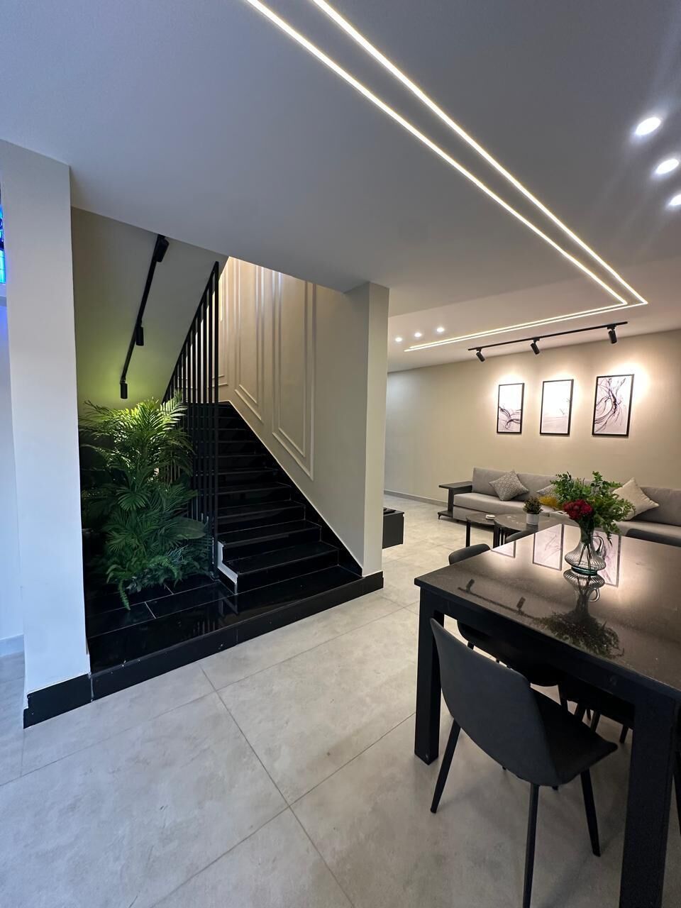 Un interior moderno con una escalera, un comedor con mesa y sillas, y un sofá en la sala.