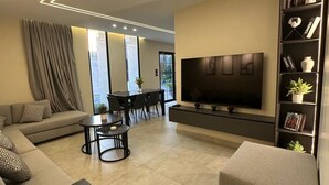 Een moderne woonkamer met een bank, salontafel, televisie en boekenkast.