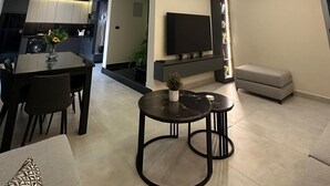 Een moderne woonkamer met een eetgedeelte, een flatscreen televisie aan de wand en een ingebouwde boekenkast.