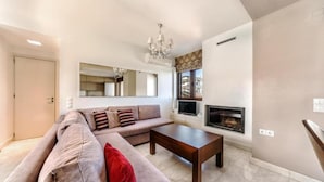 A living room with a sofa, a coffee table, a fireplace, and a chandelier. - Anastasia Suite of Sun & Sea | Bright & Comfy Cretan Getaway (Vathianos Kampos)