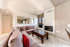 Ein Wohnzimmer mit einer Couch, einem Couchtisch, einem Kamin und einer Chandelier.