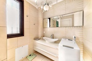 Un baño moderno con un ventanal grande, un lavabo sobre encimera, un espejo y un perchero para toallas.