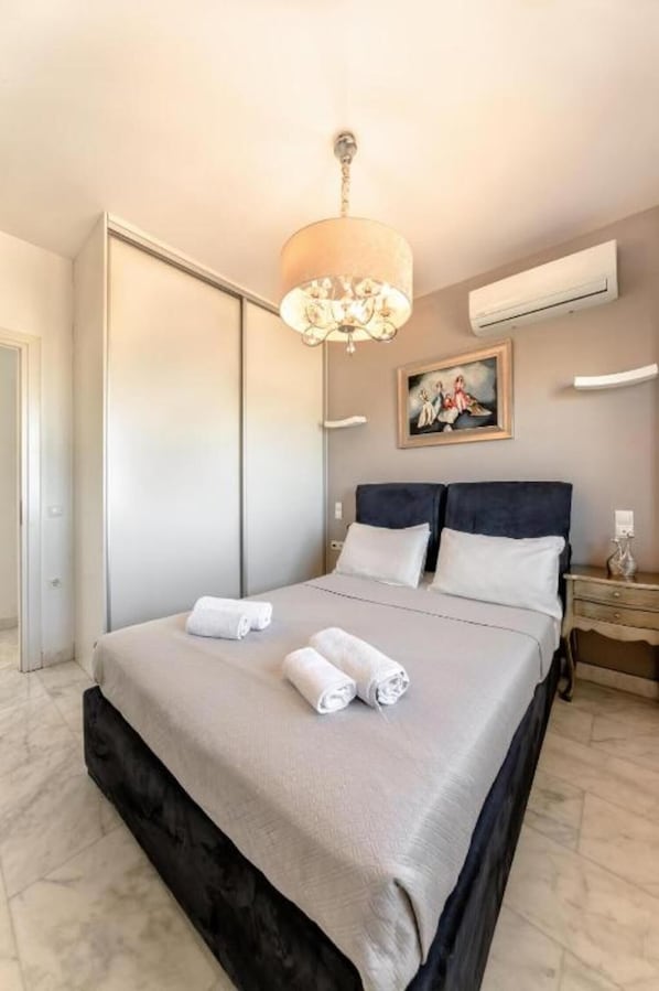 Un dormitorio con una cama, una araña, un cuadro y un equipo de aire acondicionado.