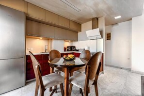 Una cocina moderna con comedor, electrodomésticos de acero inoxidable y una pared de acento roja.