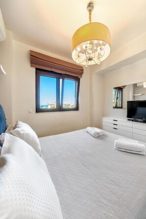 Ein Hotelzimmer mit einem Bett, einem Fernseher, einem Fenster mit Aussicht und einer Kandelaber.