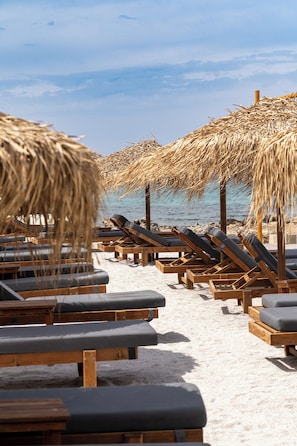 A beach with wooden lounge chairs and thatched umbrellas. - Anastasia Suite of Sun & Sea | Bright & Comfy Cretan Getaway (Vathianos Kampos)
