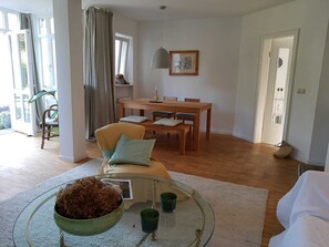 Un salón espacioso con una mesa de comedor, un sofá y una mesa baja de vidrio.