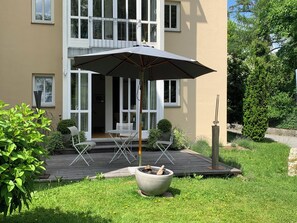 Una casa moderna con patio, un braciere e un ombrellone grande.