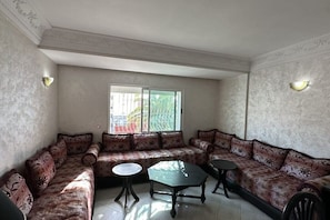 Un salon comprenant un ensemble de canapés, deux petites tables et une grande fenêtre donnant sur un paysage agréable.