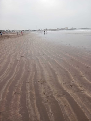 A wide sandy beach with footprints and a few people walking. - Spacious Apartment with Balcony • Beach & City Center (El Jadida)
