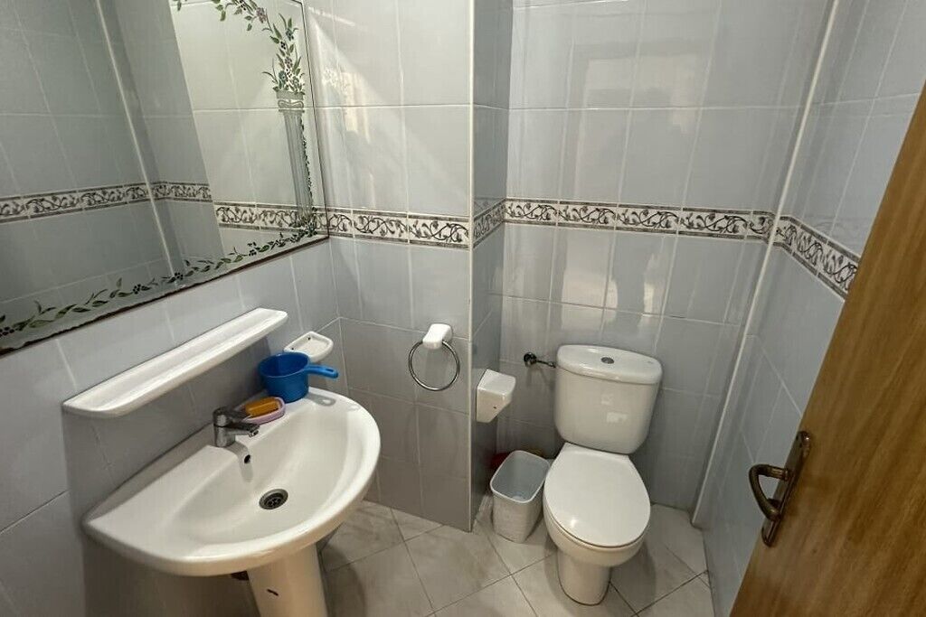 A bathroom with a sink, toilet, and a mirror.