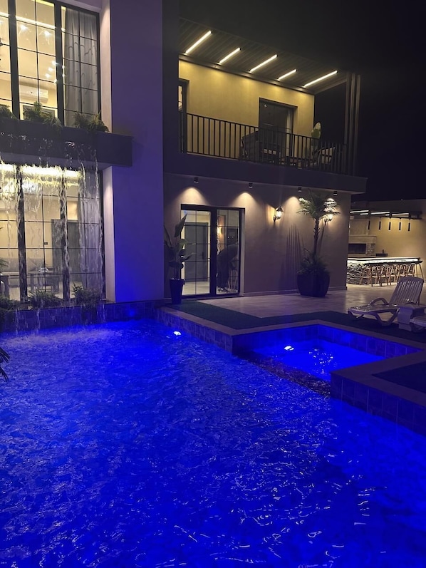 A modern house with a swimming pool, outdoor seating, and a balcony.