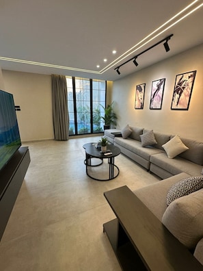 A modern living room with a sofa, coffee table, and TV. - Trio Chalet 1 (dead sea)