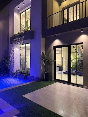 A modern building with a water feature, potted plants, and a balcony. - Trio Chalet 1 (dead sea)