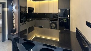 Een moderne keuken met een centraal eiland, barkrukken en inbouwapparatuur.