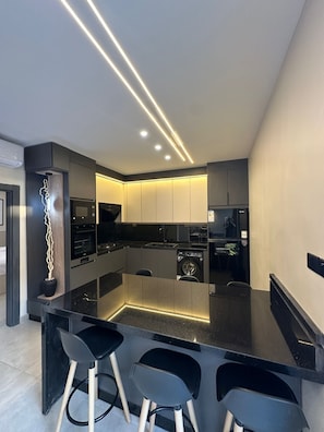 Una cocina moderna con una isla central, taburetes de bar y electrodomésticos integrados.