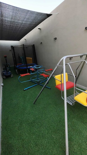 A children's play area with a trampoline, climbing structures, and a swing set. - Trio Chalet 1 (dead sea)